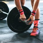 person locking gym plates on barbell